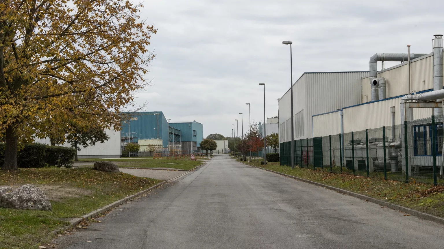 Bâtiments industriels et voie d’accès peu fréquentée sous un ciel d’automne.
